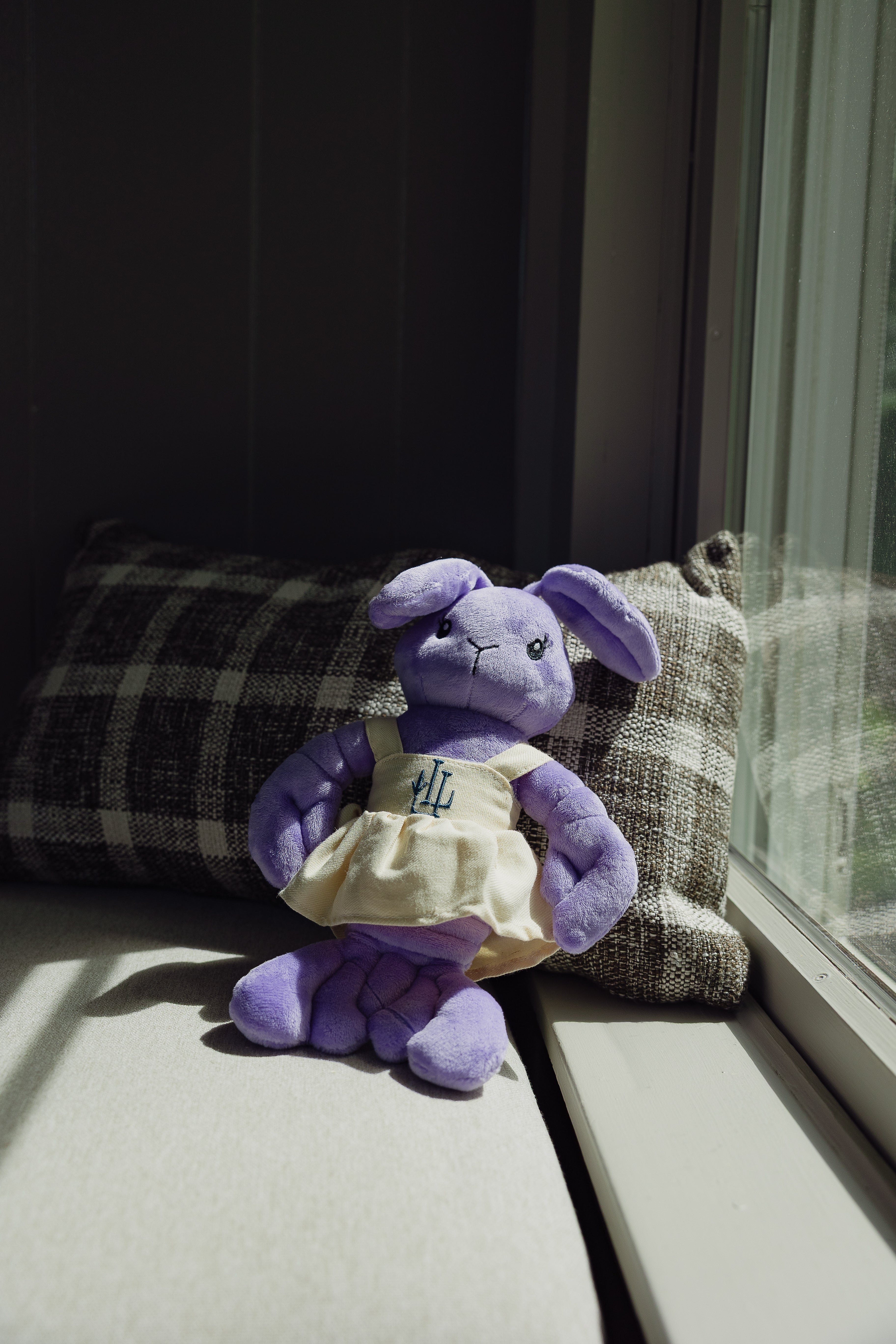 The Lavender Lobster plush toy in a linen dress with LL logo, close-up detail