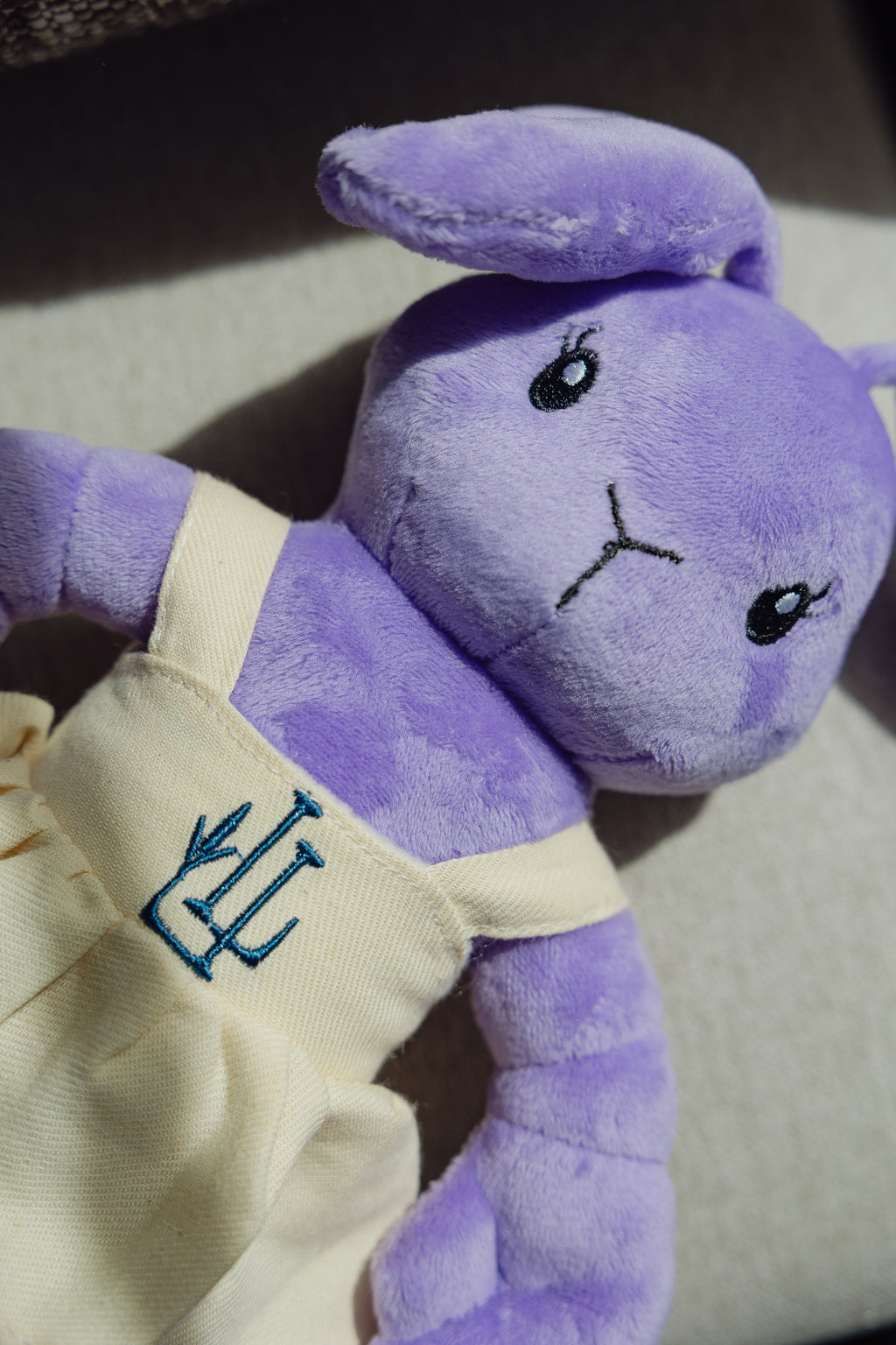 The Lavender Lobster plush toy in a linen dress with LL logo, styled shot