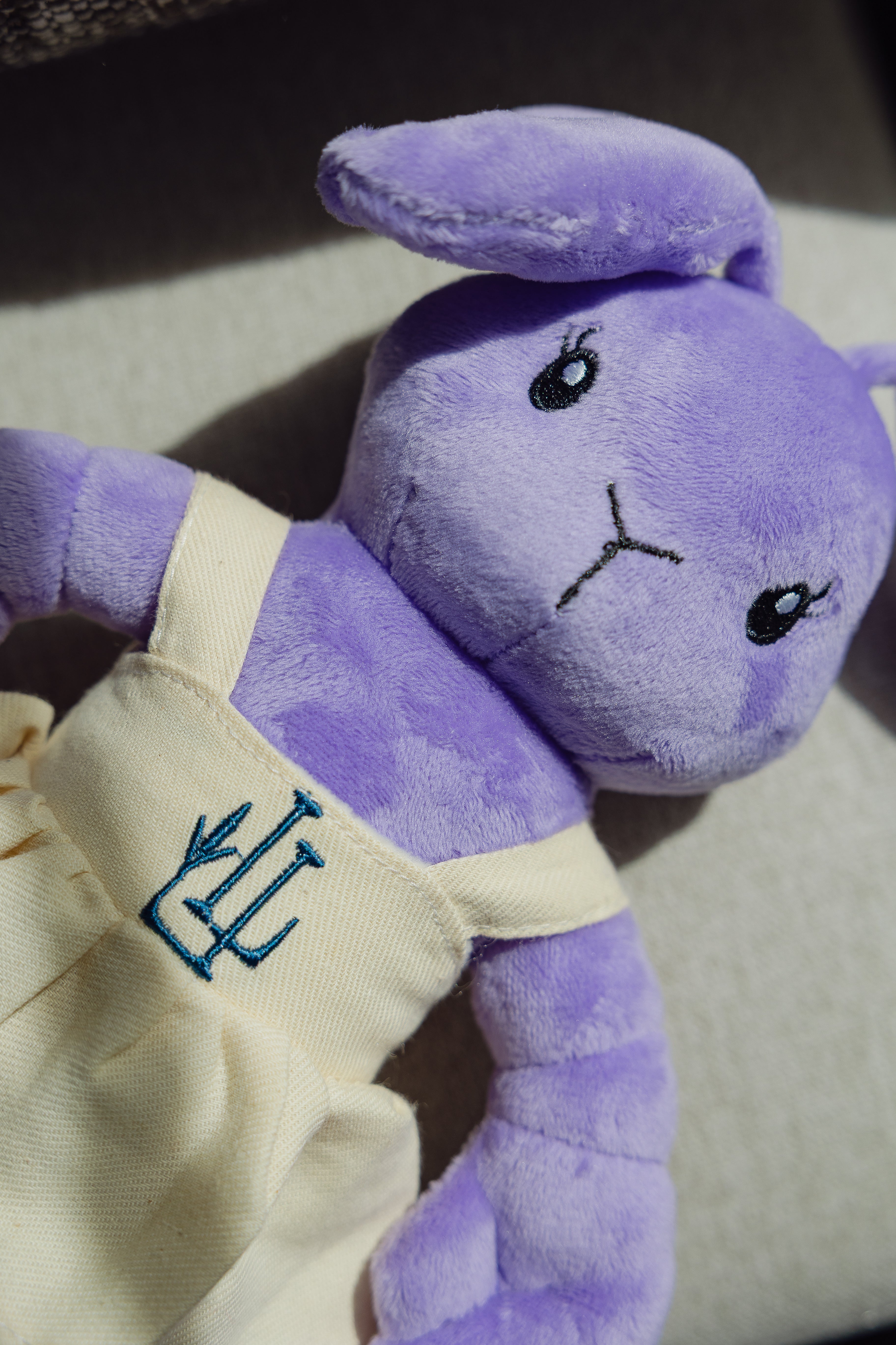 The Lavender Lobster plush toy in a linen dress with LL logo, styled shot