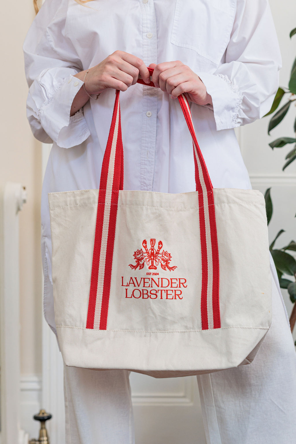 The Harbour Bag in organic cotton with striped webbing handles and crest embroidery, front view