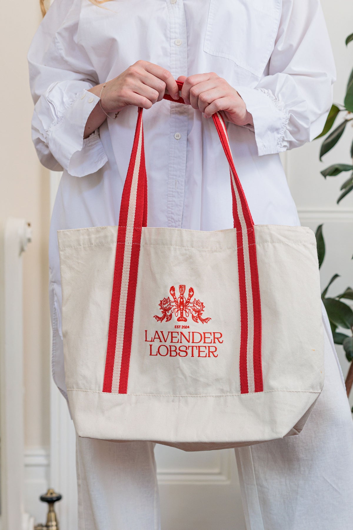 The Harbour Bag in organic cotton with striped webbing handles and crest embroidery, front view