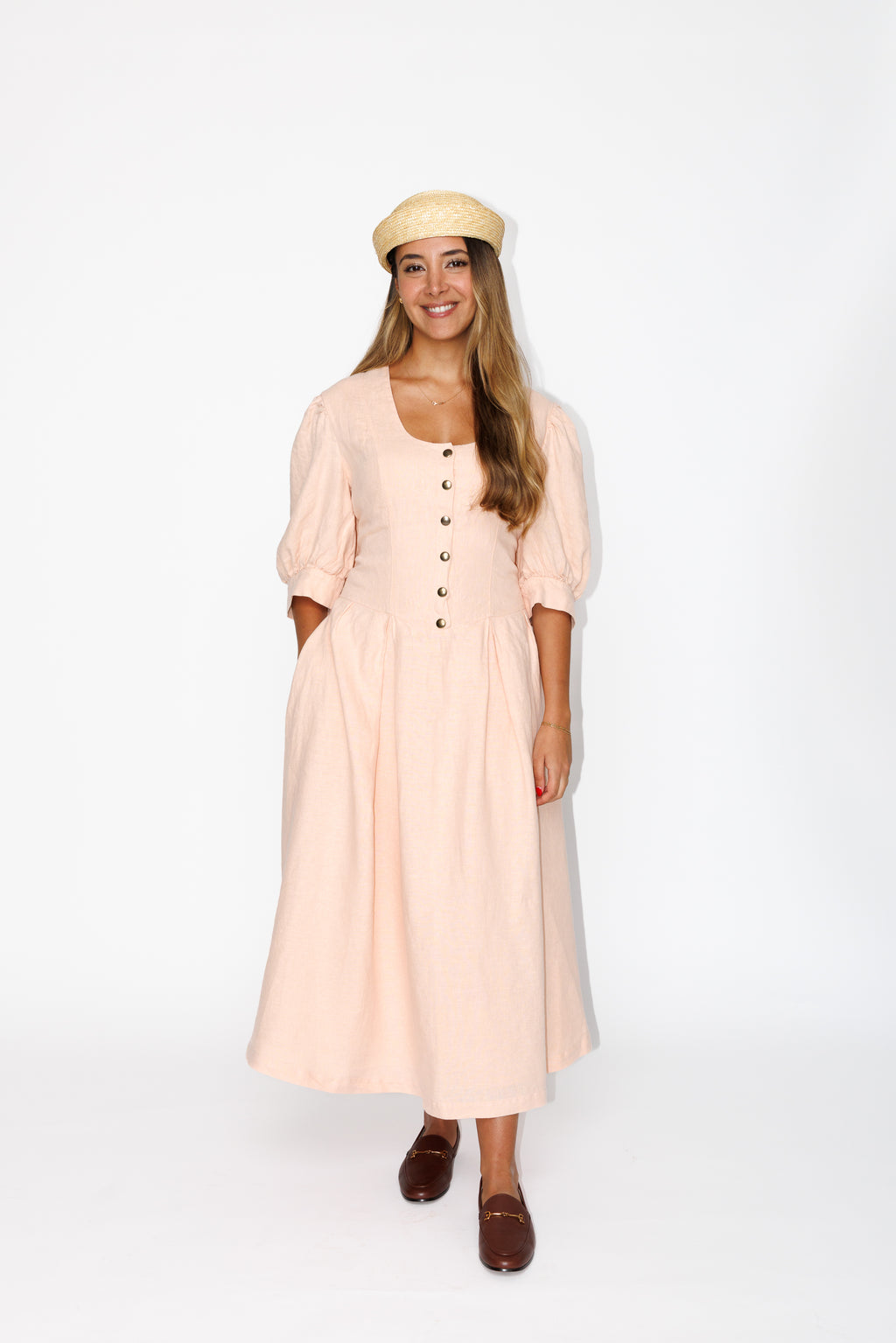 The Lobster Bisque Dress in Bisque pink organic linen, front view styled with a straw boater hat