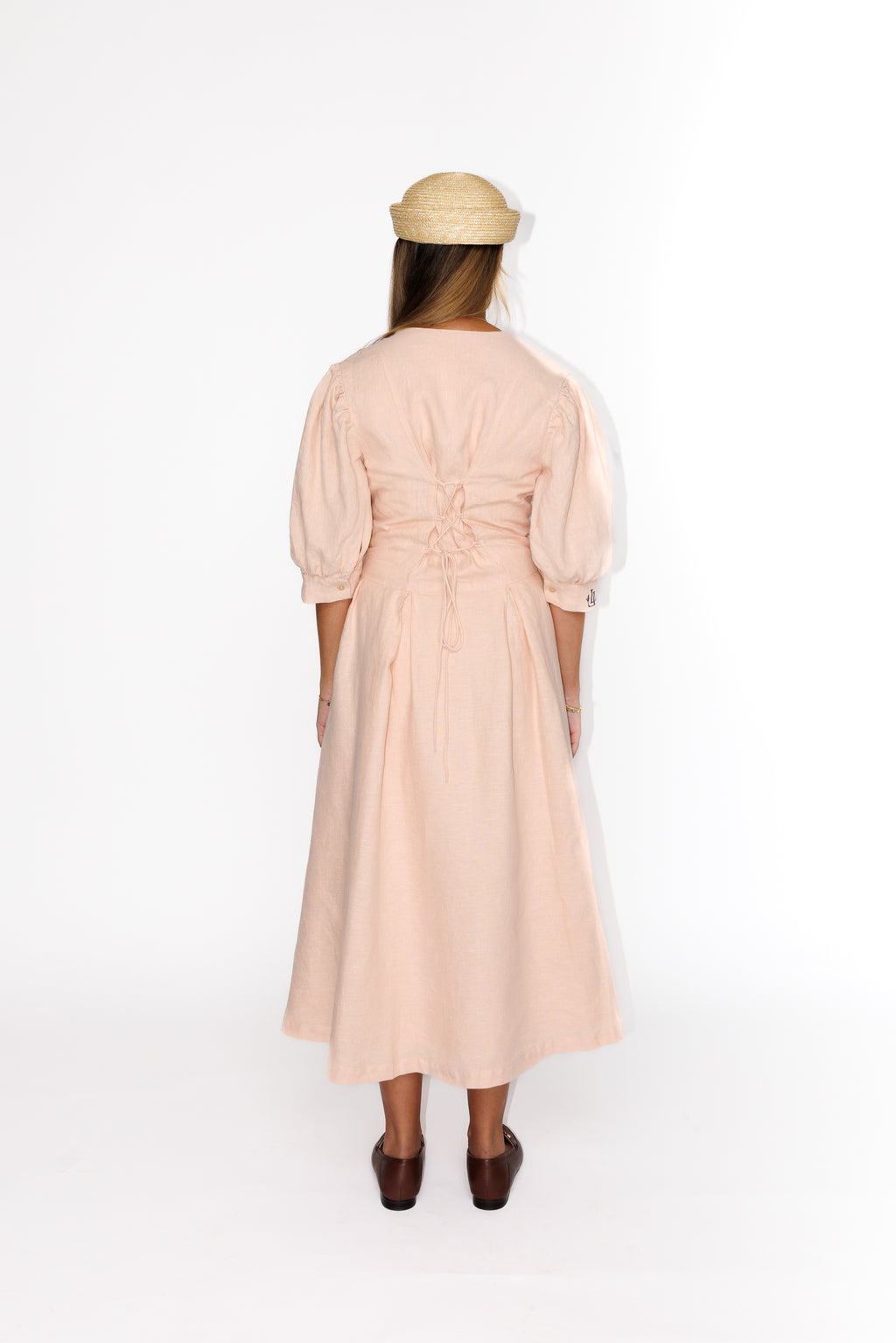 The Lobster Bisque Dress in Bisque pink organic linen, back view styled with a straw boater hat