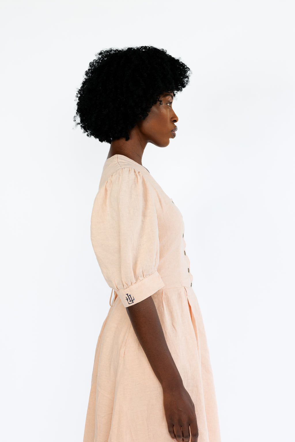 The Lobster Bisque Dress in Bisque pink organic linen, side profile detail in studio