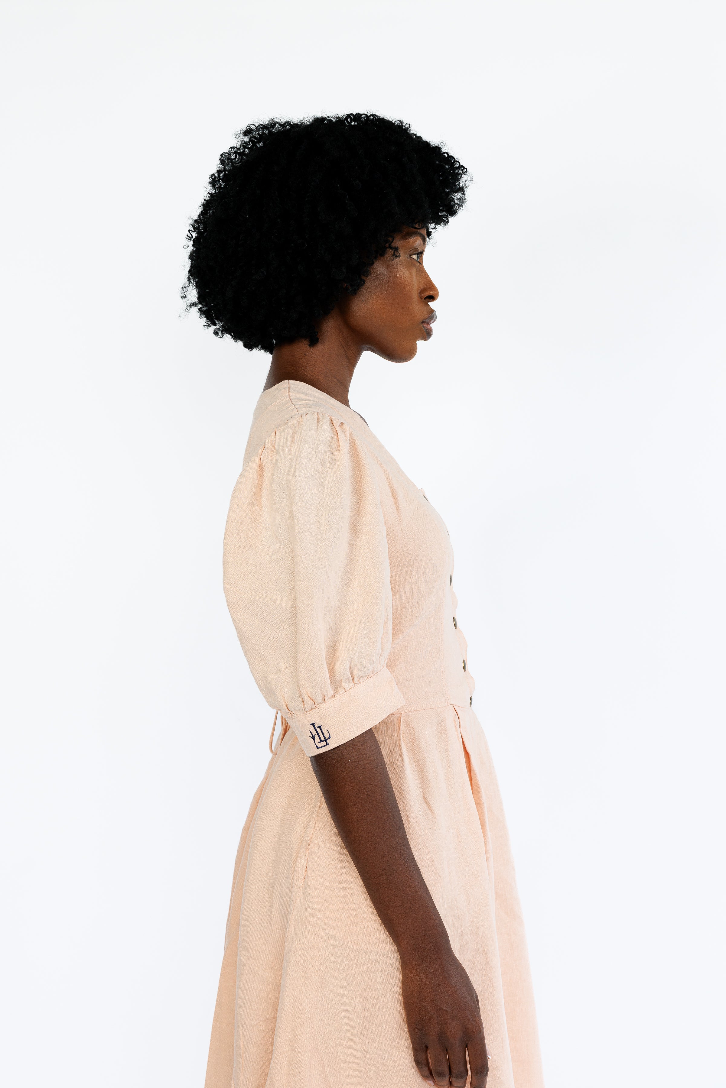 The Lobster Bisque Dress in Bisque pink organic linen, side profile detail in studio