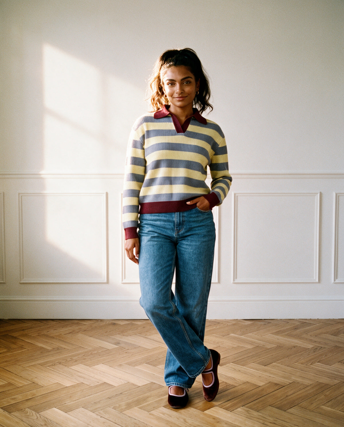 The Sports Day Rugby Shirt in lavender and butter yellow stripes with a burgundy collar, cuffs and hem, worn with straight leg jeans and burgundy velvet Mary Janes against panelled walls
